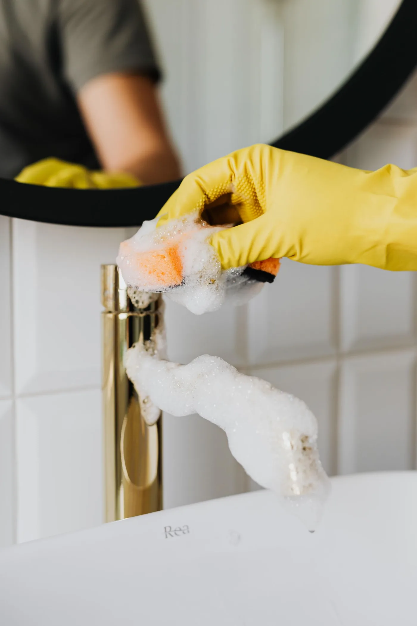 Gloved hand detailing a bathroom faucet until the fixture shines