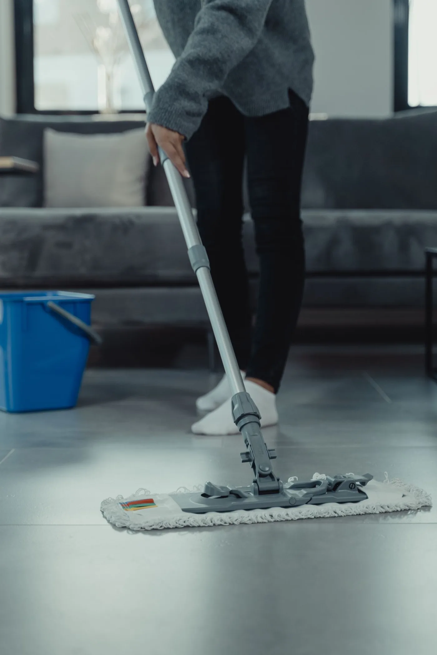 Professional cleaner mopping the tile floor of a bright family living room