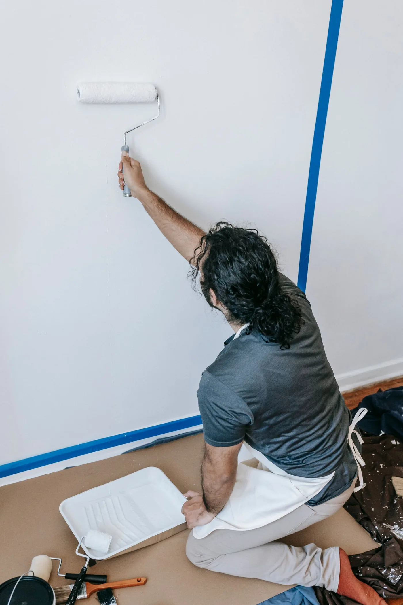 Painter rolling a fresh coat onto an interior wall during a home repaint