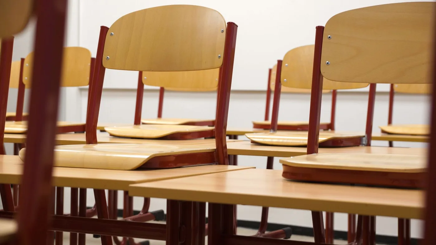 Sunlit empty classroom with clean desks arranged in neat rows