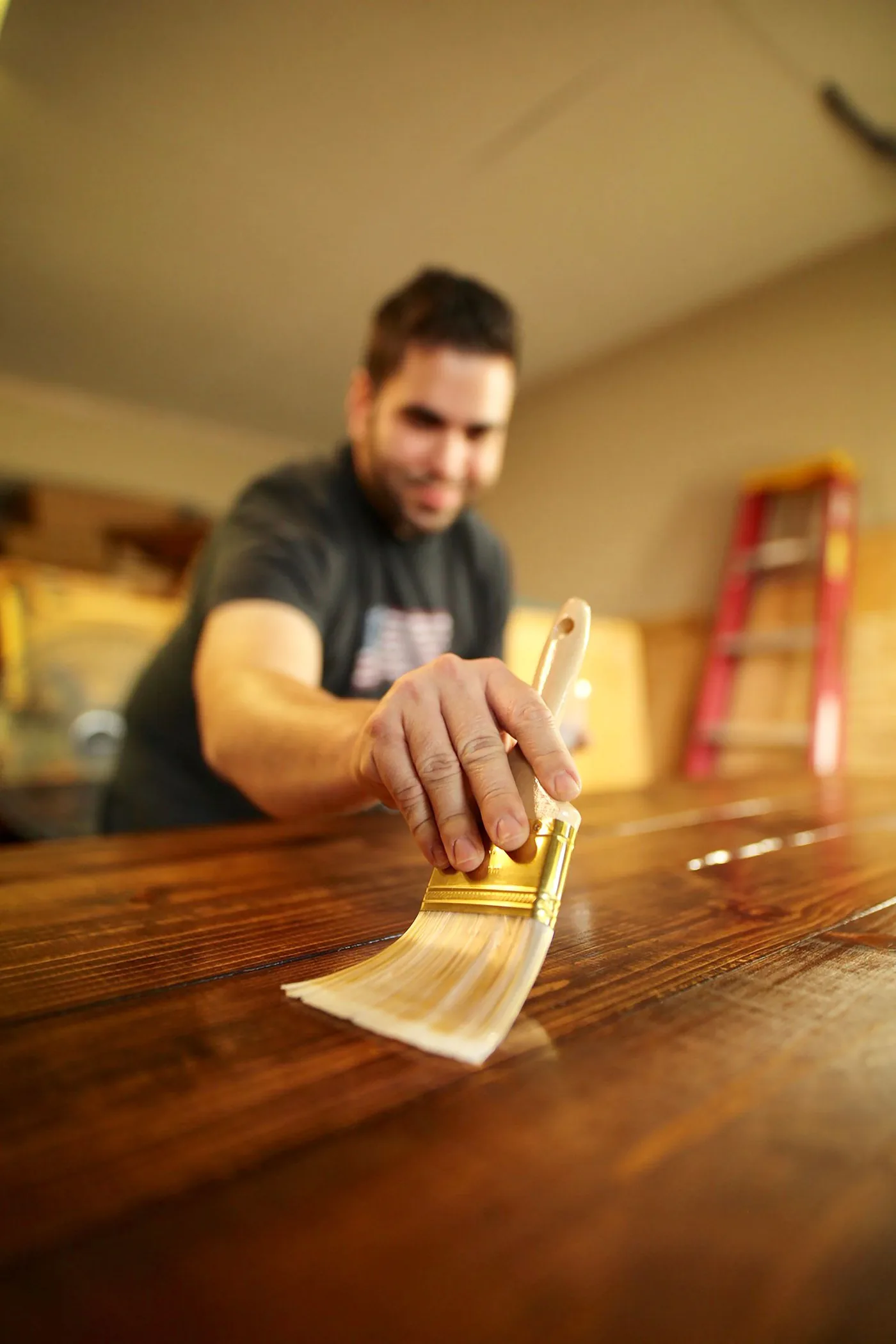 Craftsman brushing rich stain onto a wooden surface, grain showing through