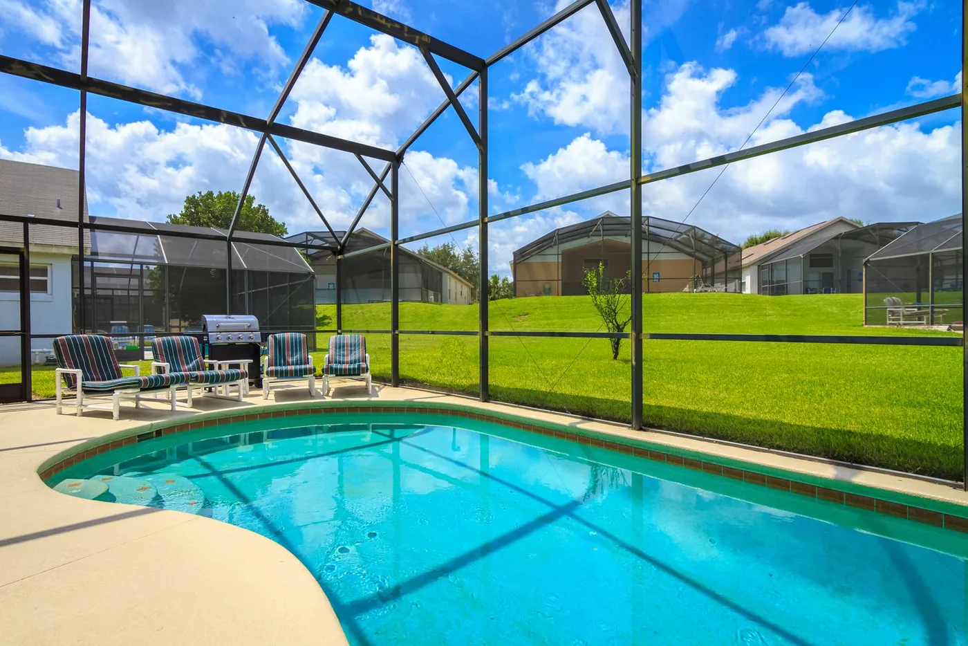 Sunny screened pool deck of a Florida vacation villa with lounge chairs
